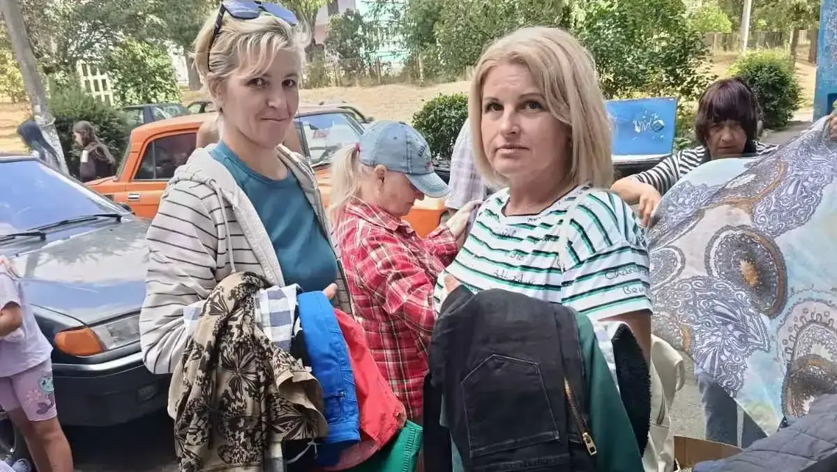 Twee vrouwen tonen de kleding die ze hebben gekregen