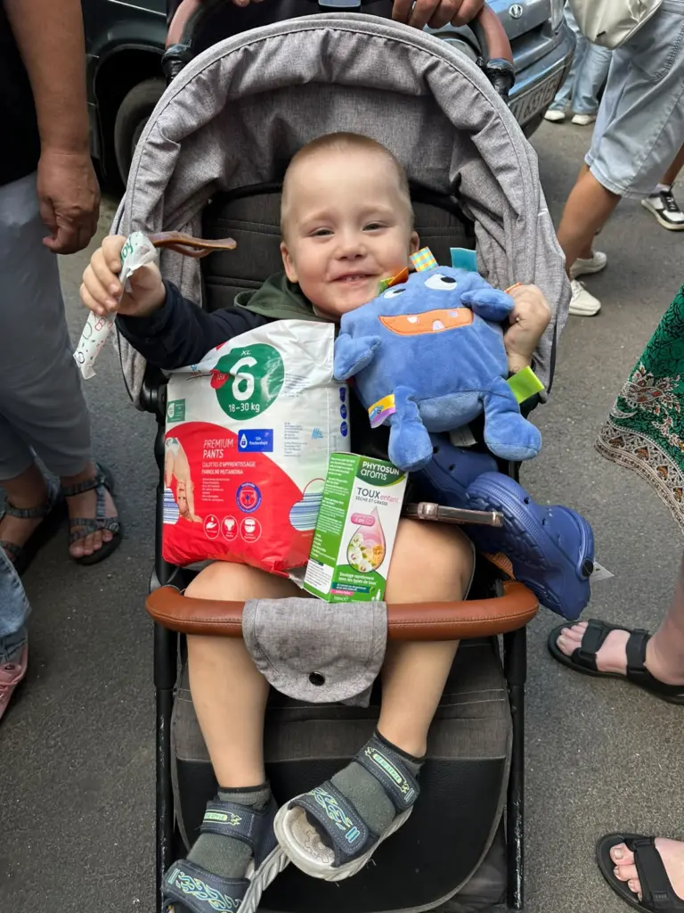 Jongen in buggy toont de gekregen spullen.